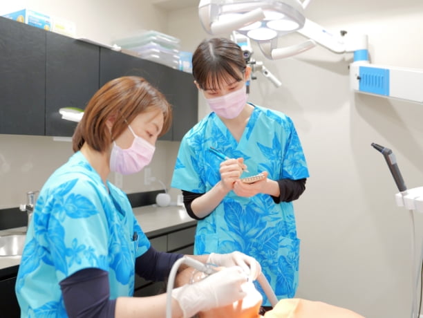 短い時間でプラークの取り残しがないように処置するために処置方法を教えている様子